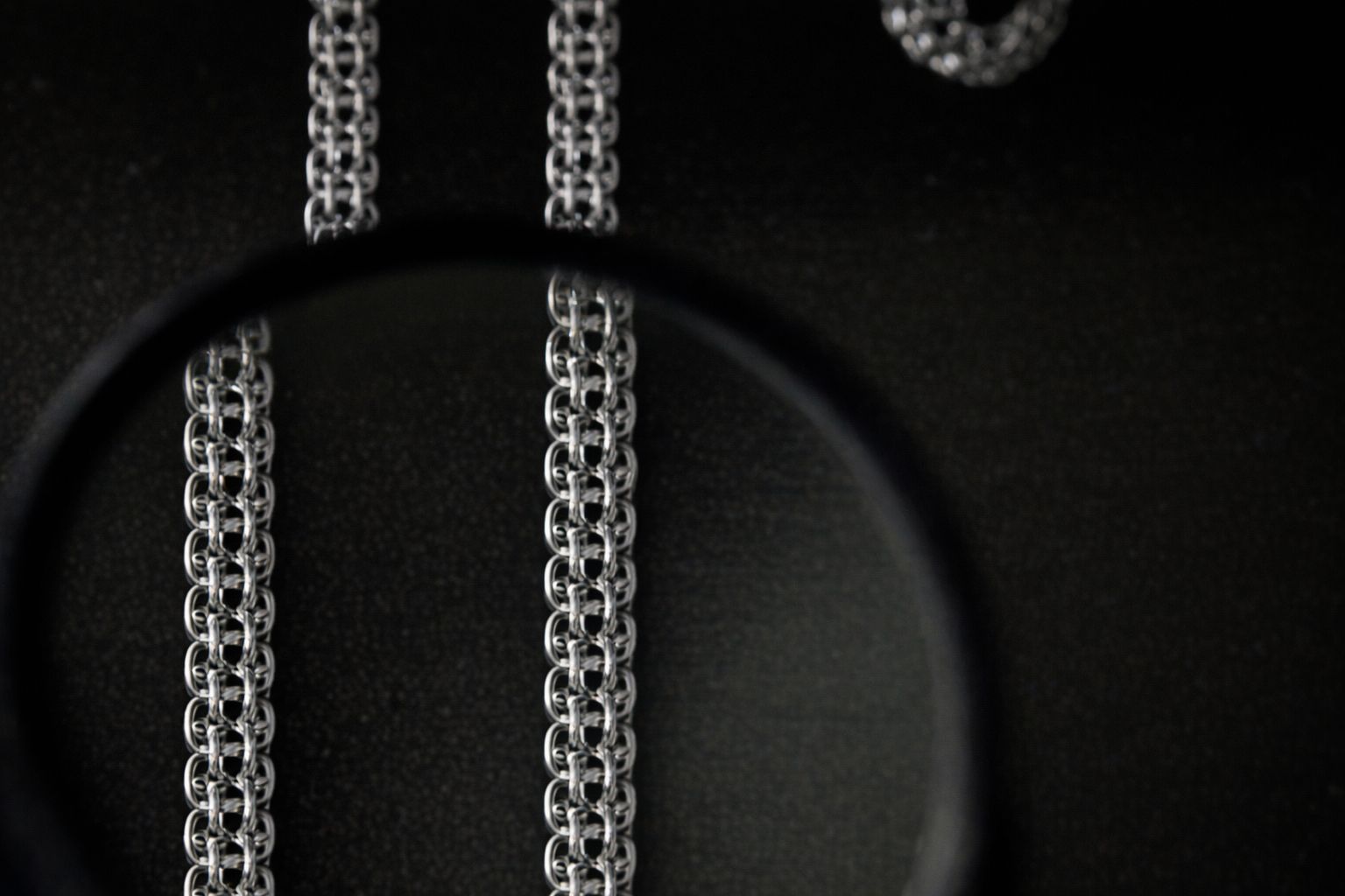 Närbild på ett bismarckarmband i silver mot en mörk bakgrund.